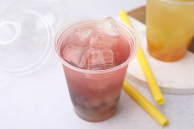 Photo of Tasty bubble tea in plastic cups and straws on light table, closeup