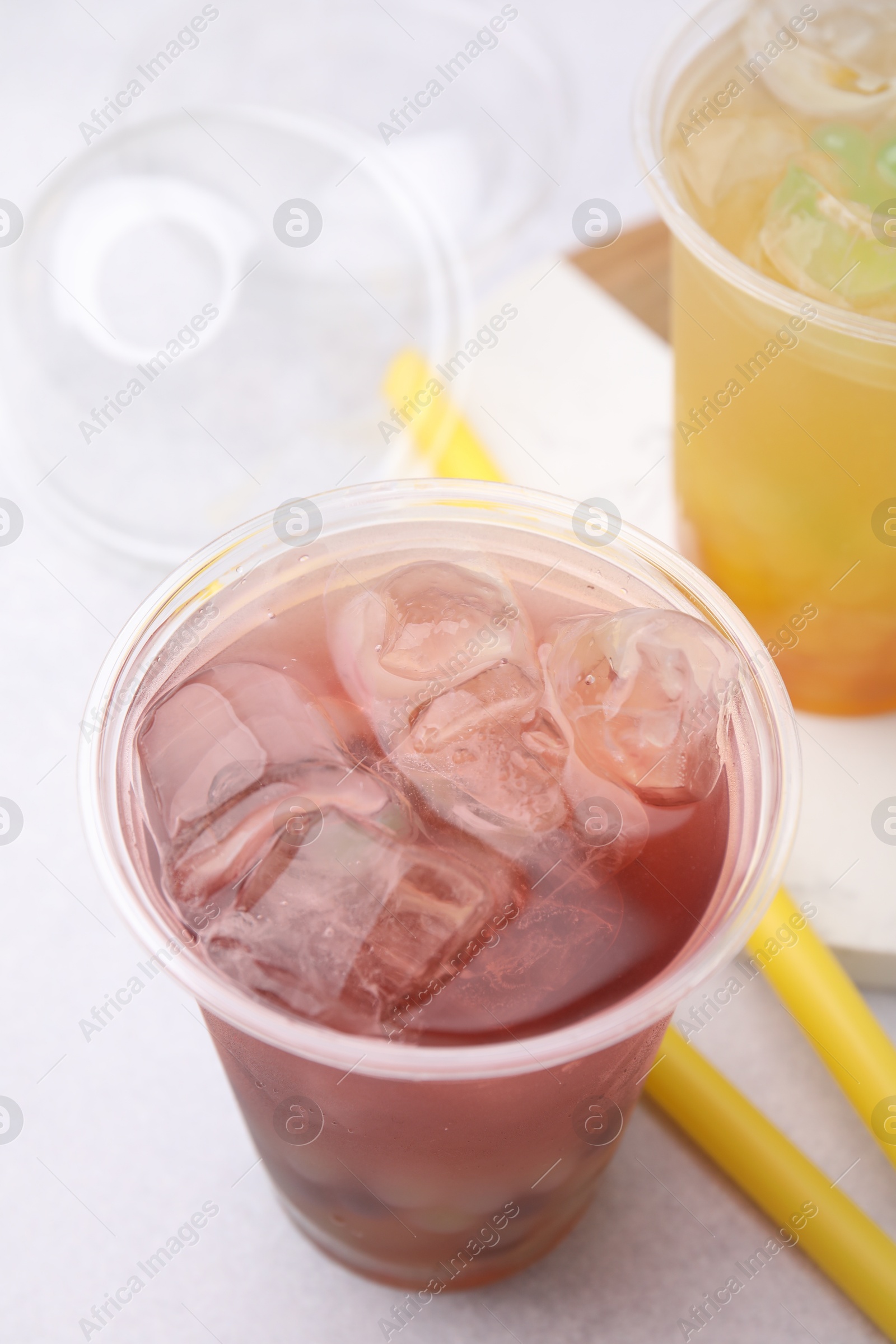 Photo of Tasty bubble tea in plastic cups and straws on light table, closeup