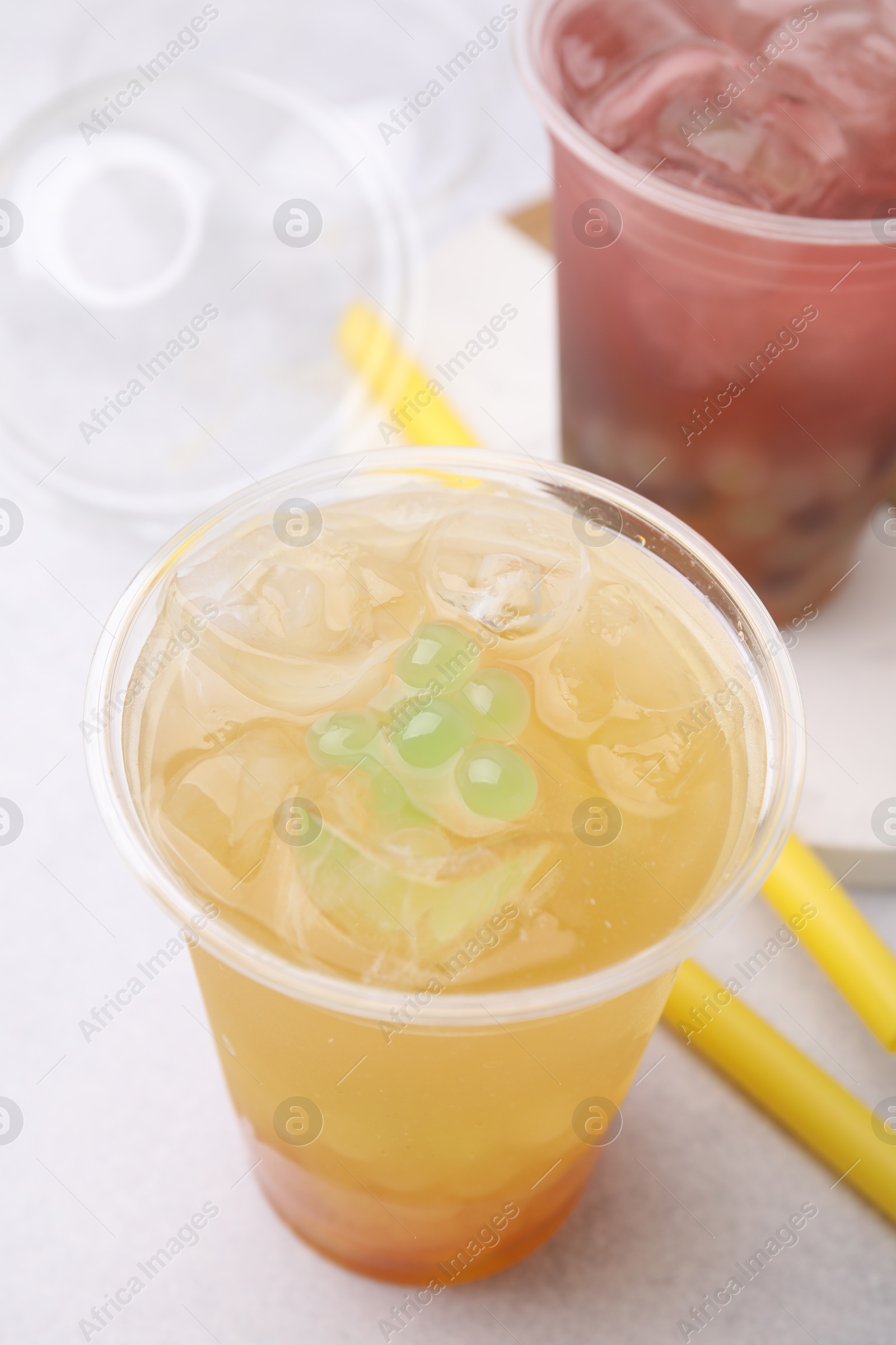 Photo of Tasty bubble tea in plastic cups and straws on light table, closeup