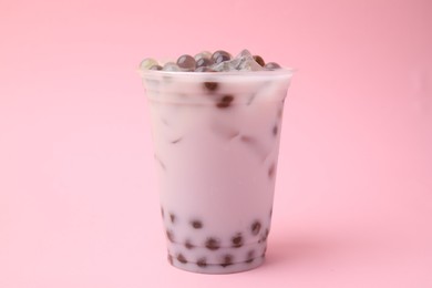 Photo of Tasty milk bubble tea in plastic cup on pink background