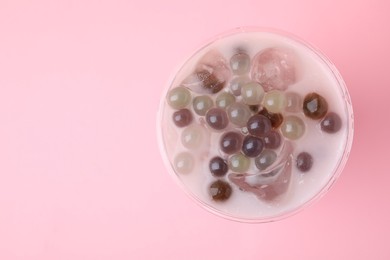 Photo of Tasty milk bubble tea in plastic cup on pink background, top view. Space for text