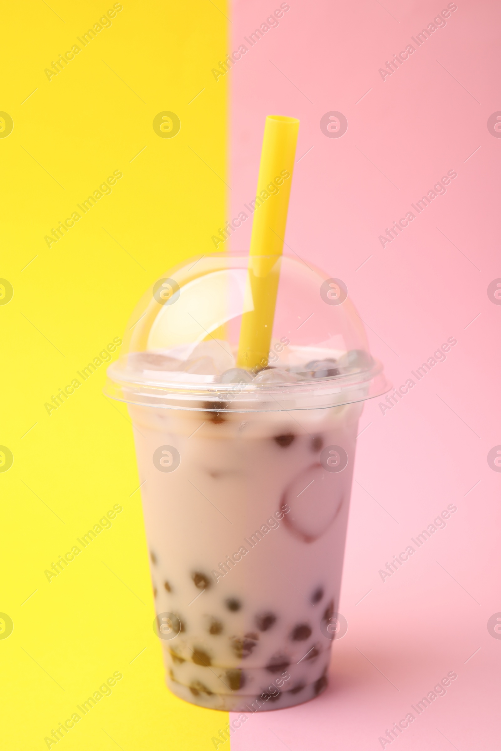 Photo of Tasty milk bubble tea in plastic cup on color background