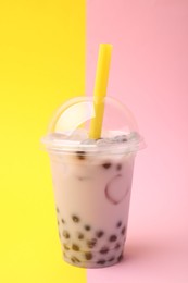 Photo of Tasty milk bubble tea in plastic cup on color background