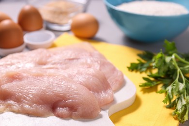 Photo of Cooking schnitzel. Raw meat and parsley on table, closeup