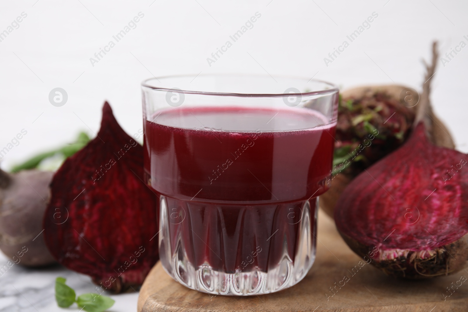 Photo of Fresh beet juice in glass and ripe vegetables on table, closeup