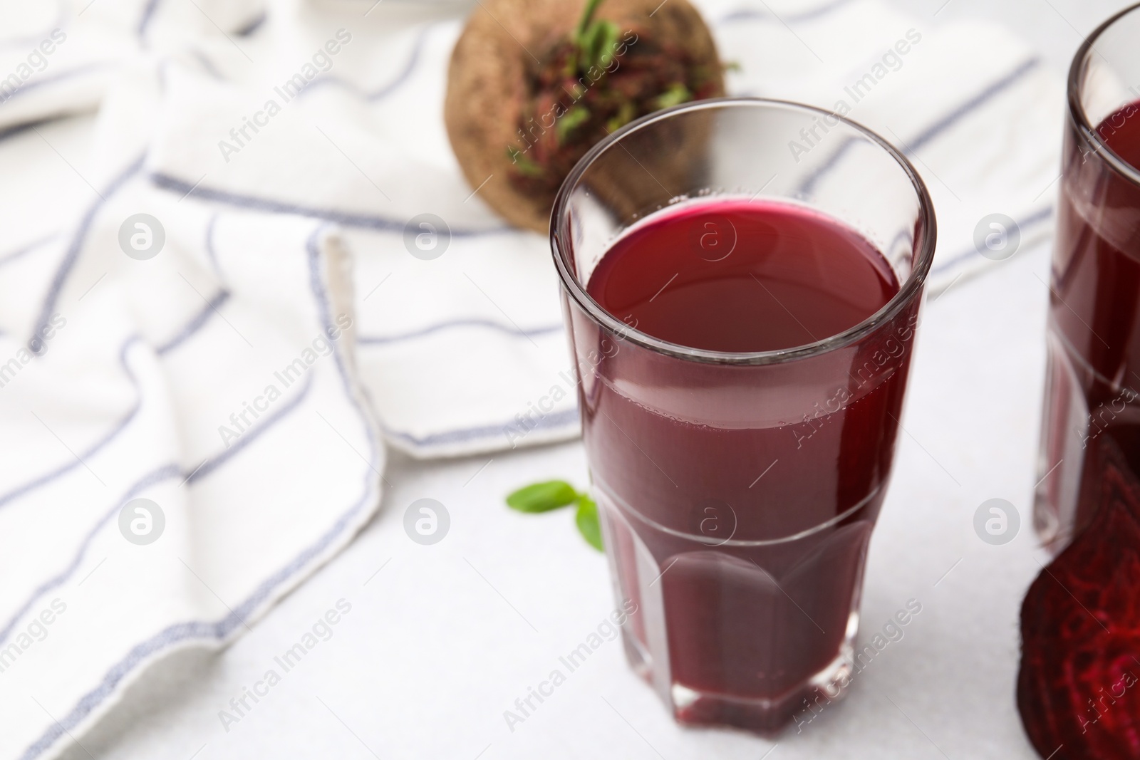 Photo of Fresh beet juice in glass on light table, closeup. Space for text