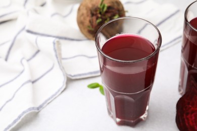 Photo of Fresh beet juice in glass on light table, closeup. Space for text