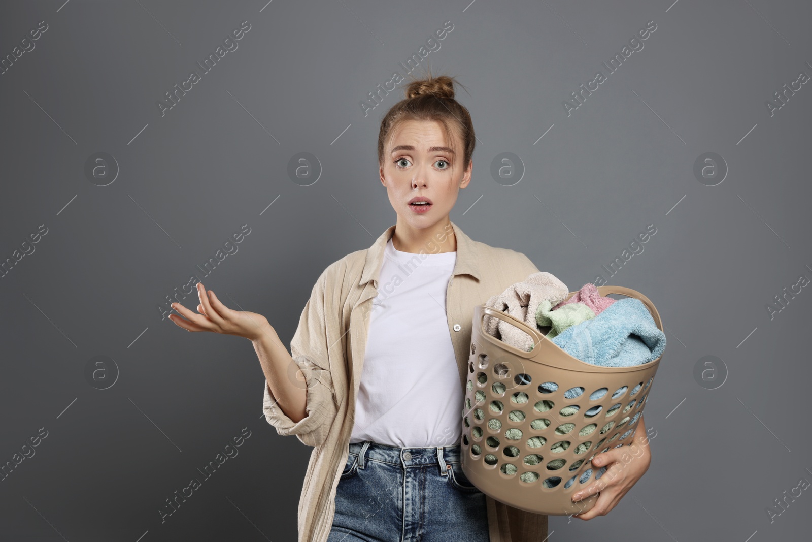 Photo of Tired housewife with basket full of laundry on grey background