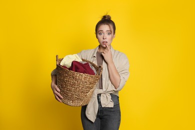 Photo of Tired housewife with basket full of laundry on yellow background