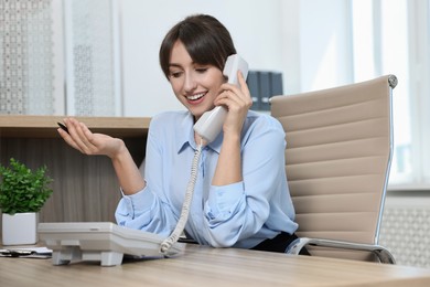 Professional receptionist talking on phone in office