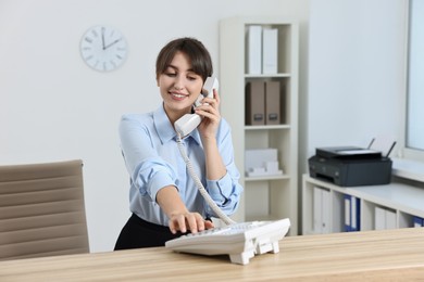 Professional receptionist talking on phone in office