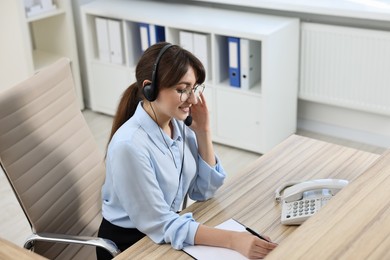 Professional receptionist working at wooden desk in office