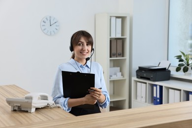 Professional receptionist working at wooden desk in office