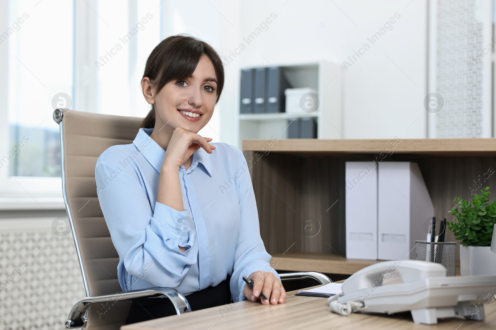 Photo of Portrait of receptionist at wooden desk in office