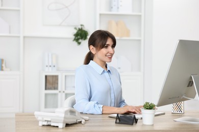 Professional receptionist working at wooden desk in office