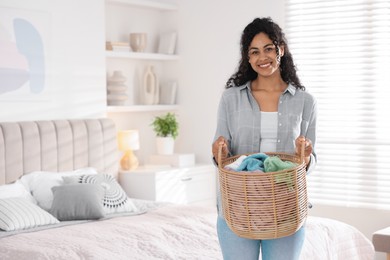 Happy woman with basket full of laundry in bedroom