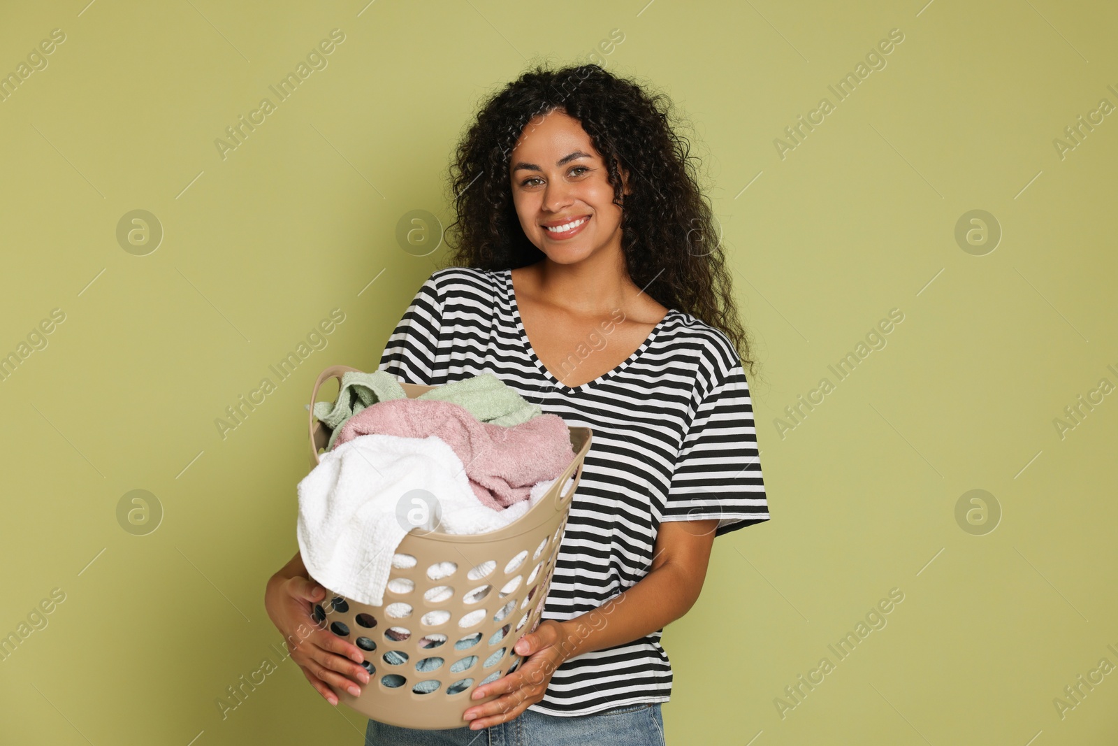 Photo of Happy woman with basket full of laundry on olive background