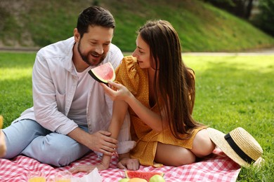 Lovely couple having picnic on green grass outdoors