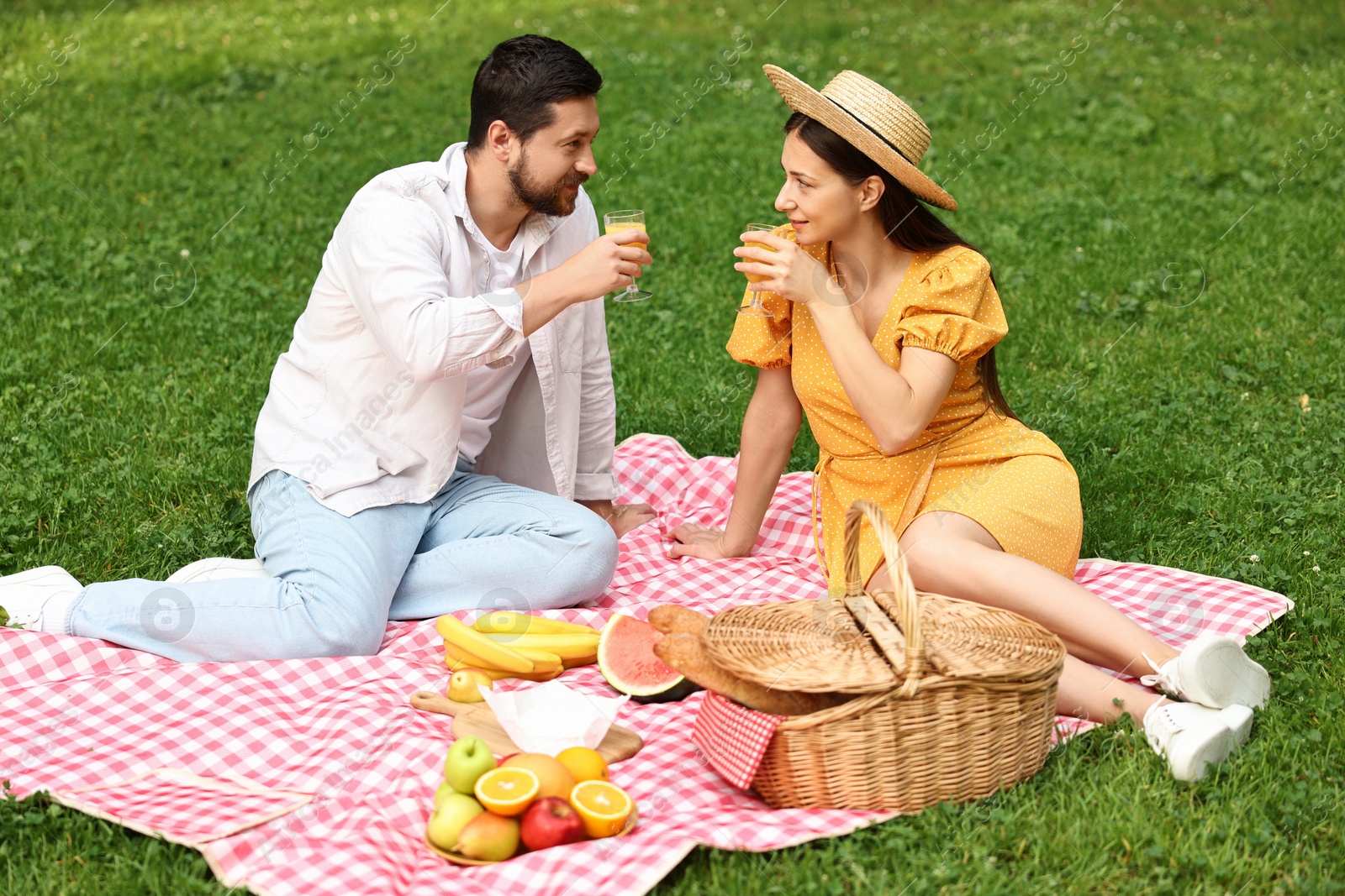 Photo of Lovely couple having picnic on green grass outdoors