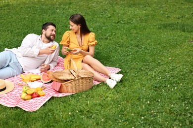 Photo of Lovely couple having picnic on green grass outdoors. Space for text