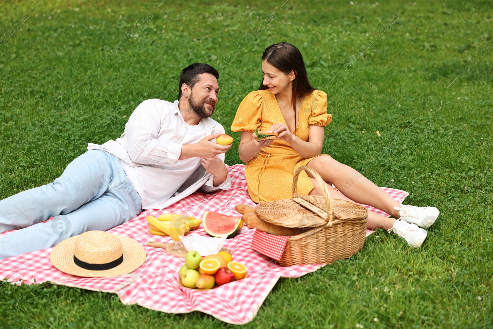 Photo of Lovely couple having picnic on green grass outdoors