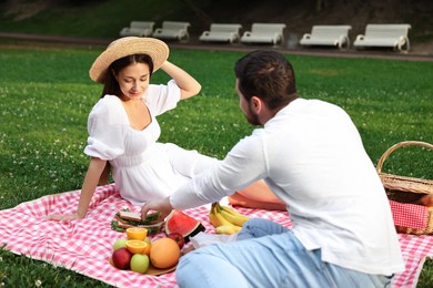 Lovely couple having picnic on green grass outdoors