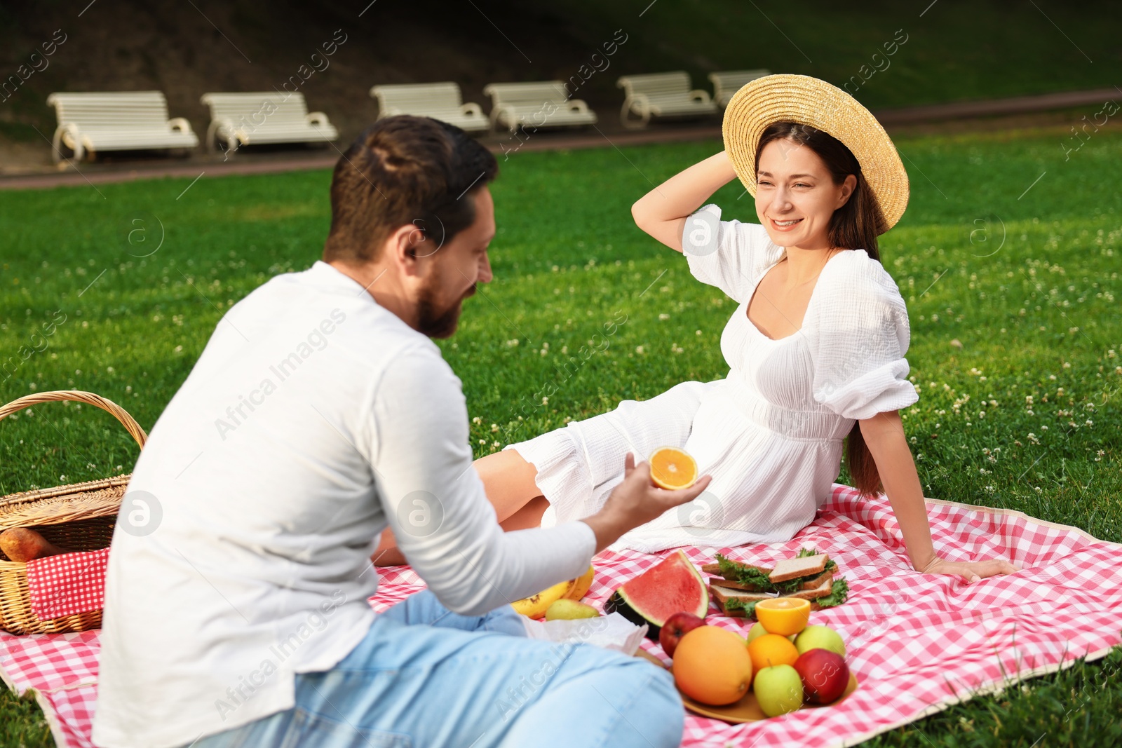 Photo of Lovely couple having picnic on green grass outdoors