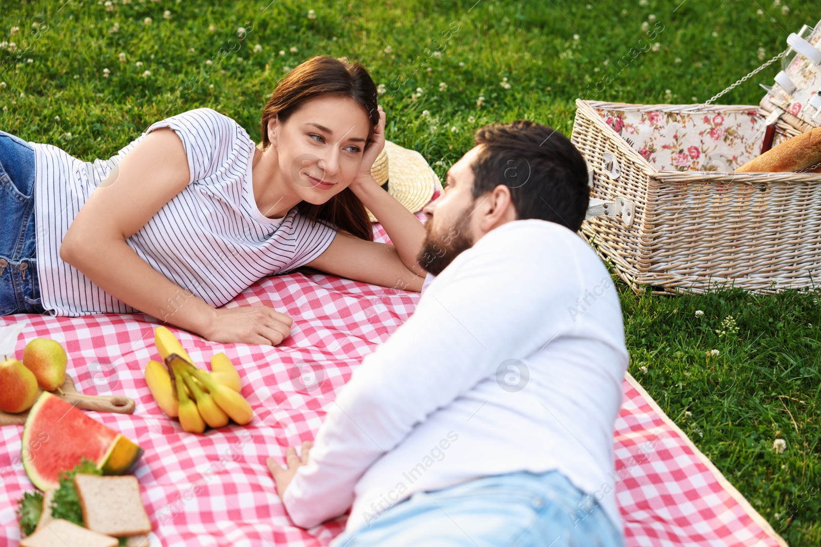 Photo of Lovely couple having picnic on green grass outdoors