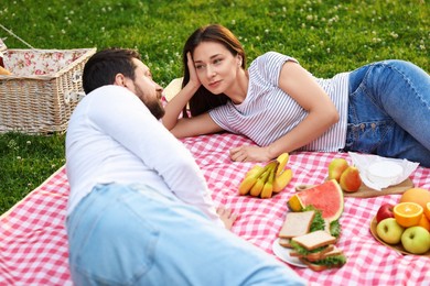 Lovely couple having picnic on green grass outdoors