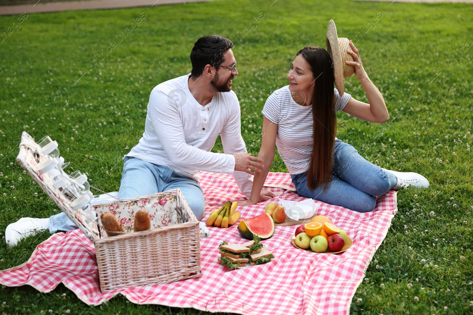 Photo of Happy couple having picnic on green grass outdoors