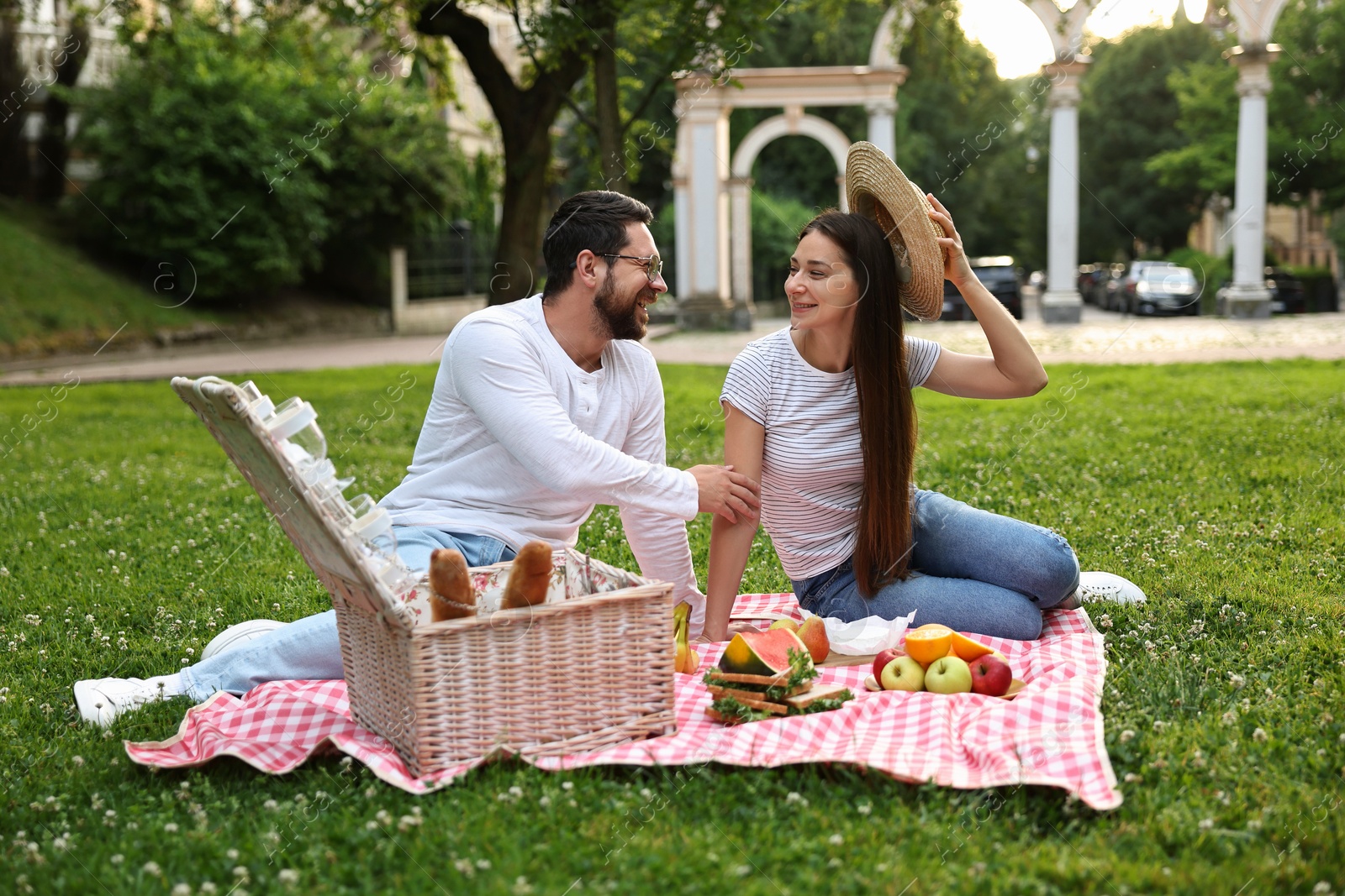 Photo of Happy couple having picnic on green grass outdoors