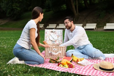 Lovely couple having picnic on green grass outdoors