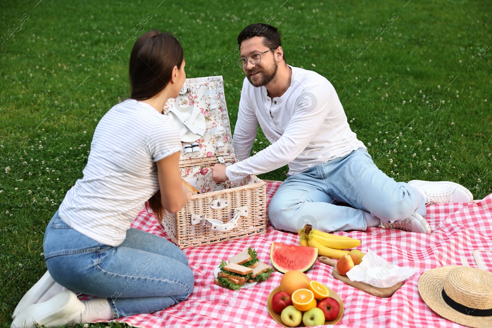 Photo of Happy couple having picnic on green grass outdoors