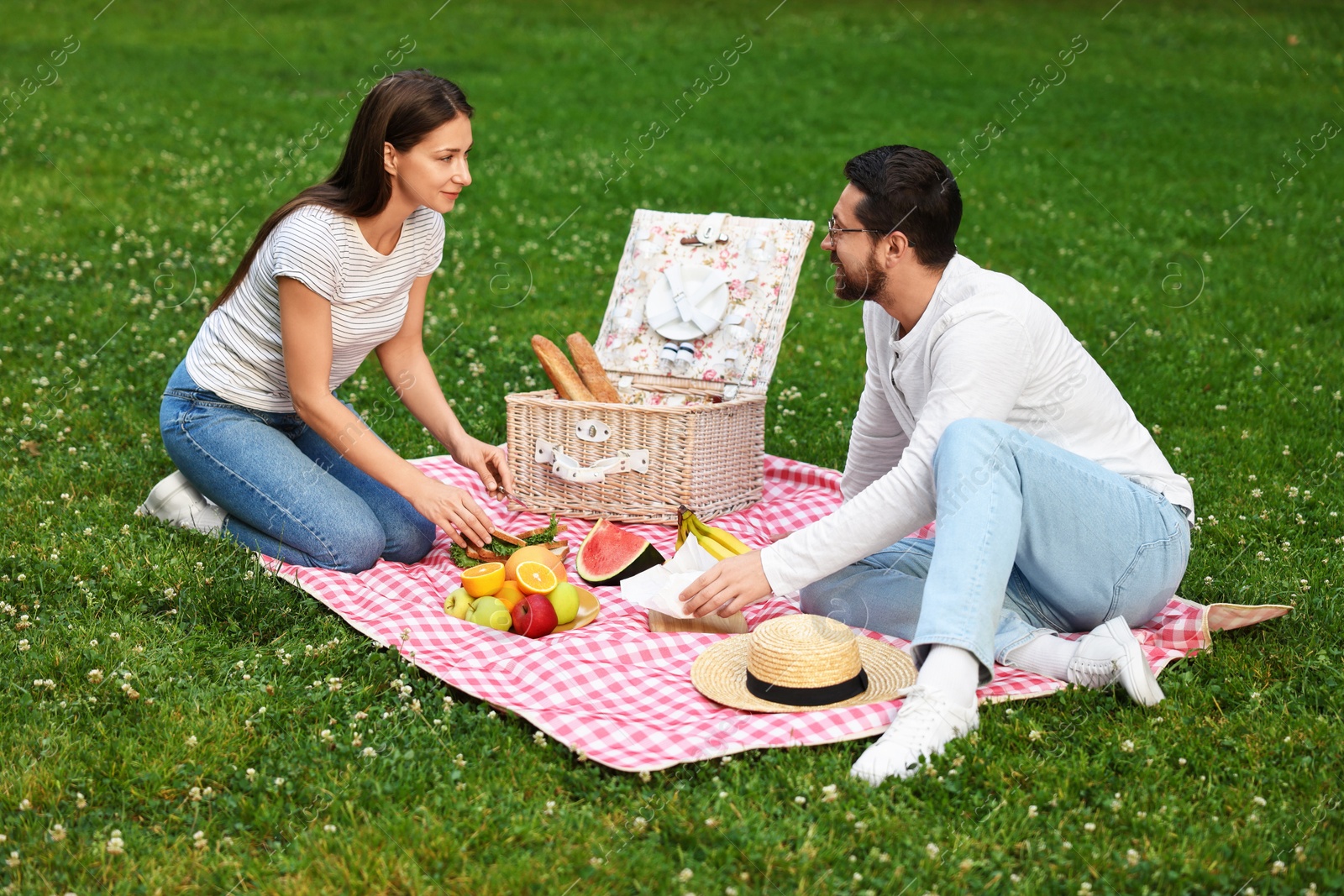 Photo of Lovely couple having picnic on green grass outdoors