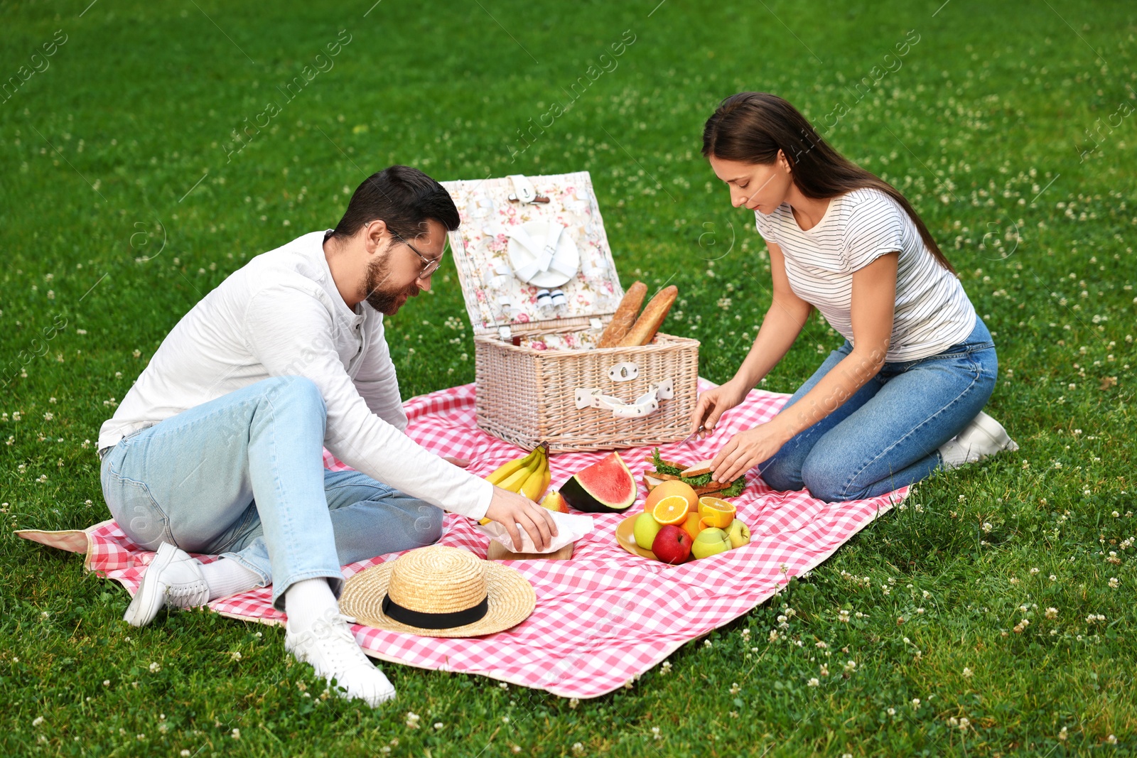 Photo of Lovely couple having picnic on green grass outdoors