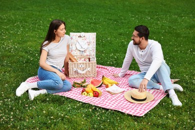 Lovely couple having picnic on green grass outdoors