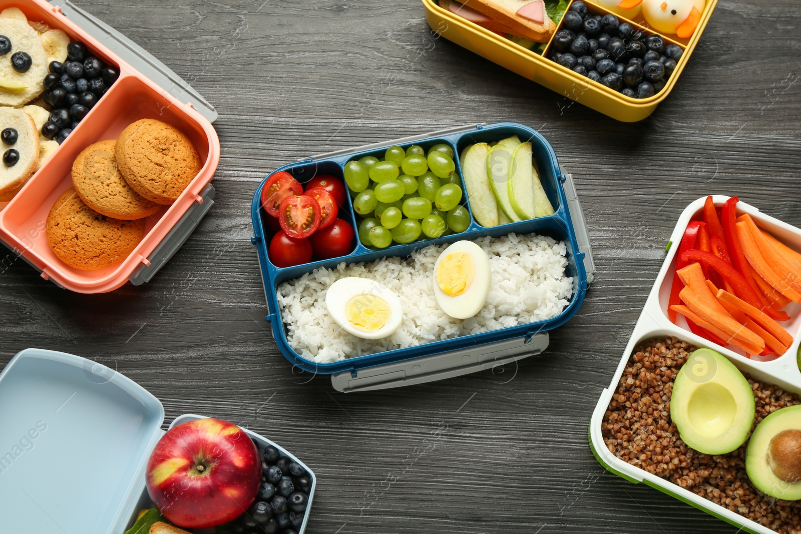 Photo of Lunch boxes with different snacks on wooden table, flat lay