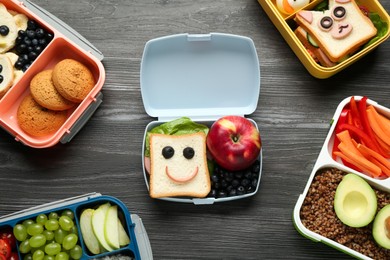 Photo of Lunch boxes with different snacks on wooden table, flat lay