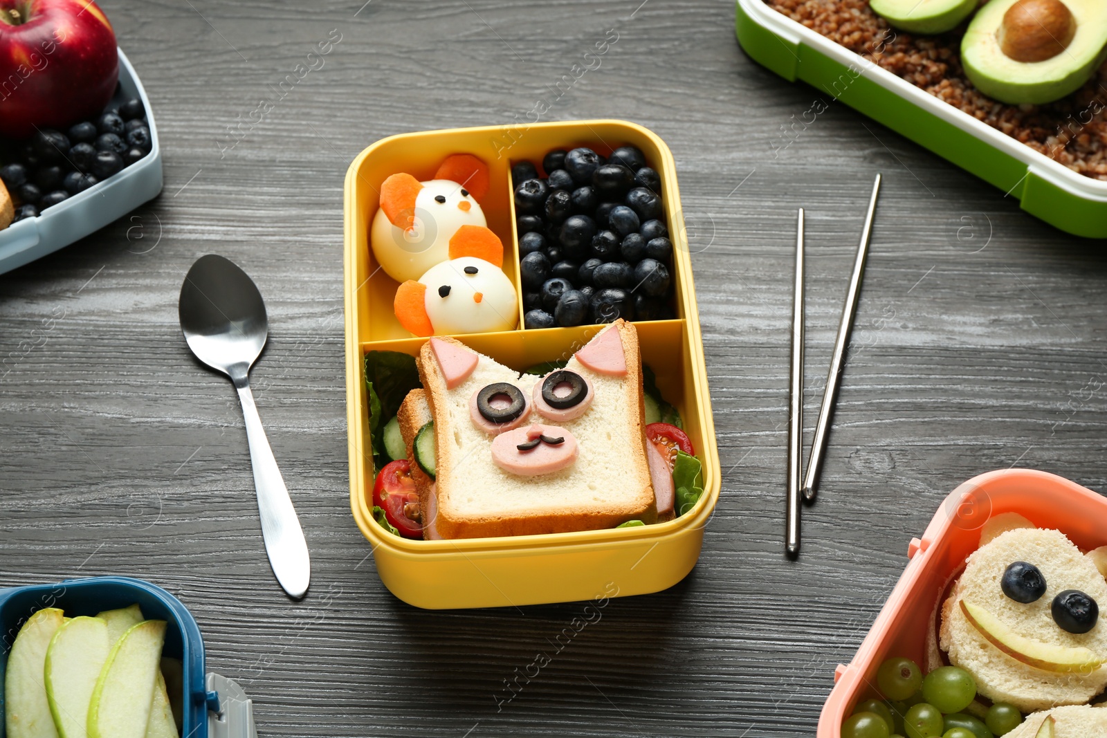 Photo of Lunch boxes with different snacks and cutlery on wooden table, above view