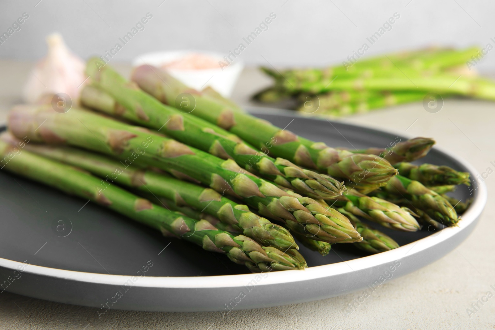 Photo of Fresh green asparagus stems on gray table, closeup