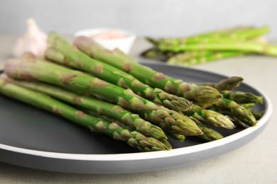 Photo of Fresh green asparagus stems on gray table, closeup