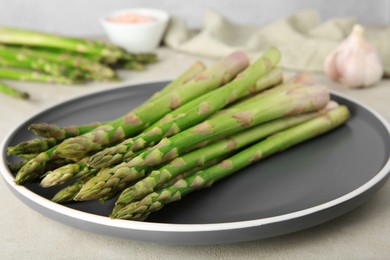 Photo of Fresh green asparagus stems on gray table, closeup