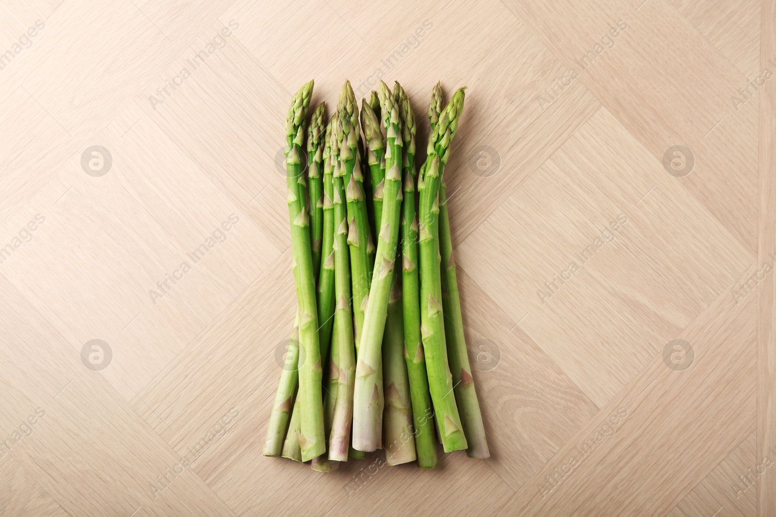 Photo of Fresh green asparagus stems on wooden table, top view