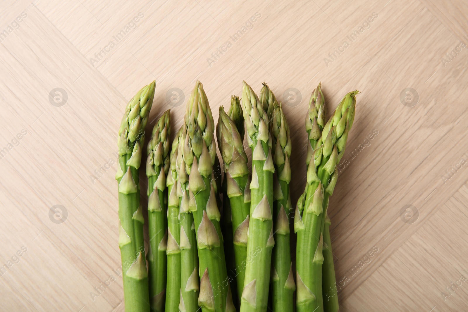 Photo of Fresh green asparagus stems on wooden table, top view