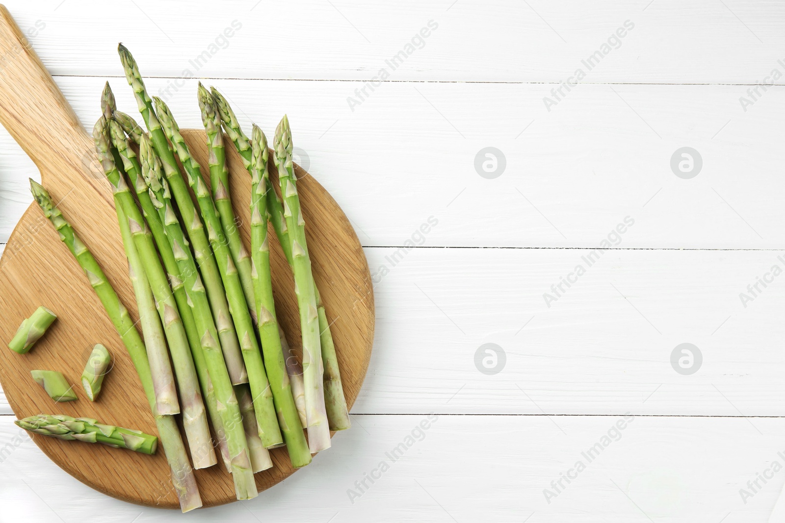 Photo of Fresh green asparagus stems on white wooden table, flat lay. Space for text