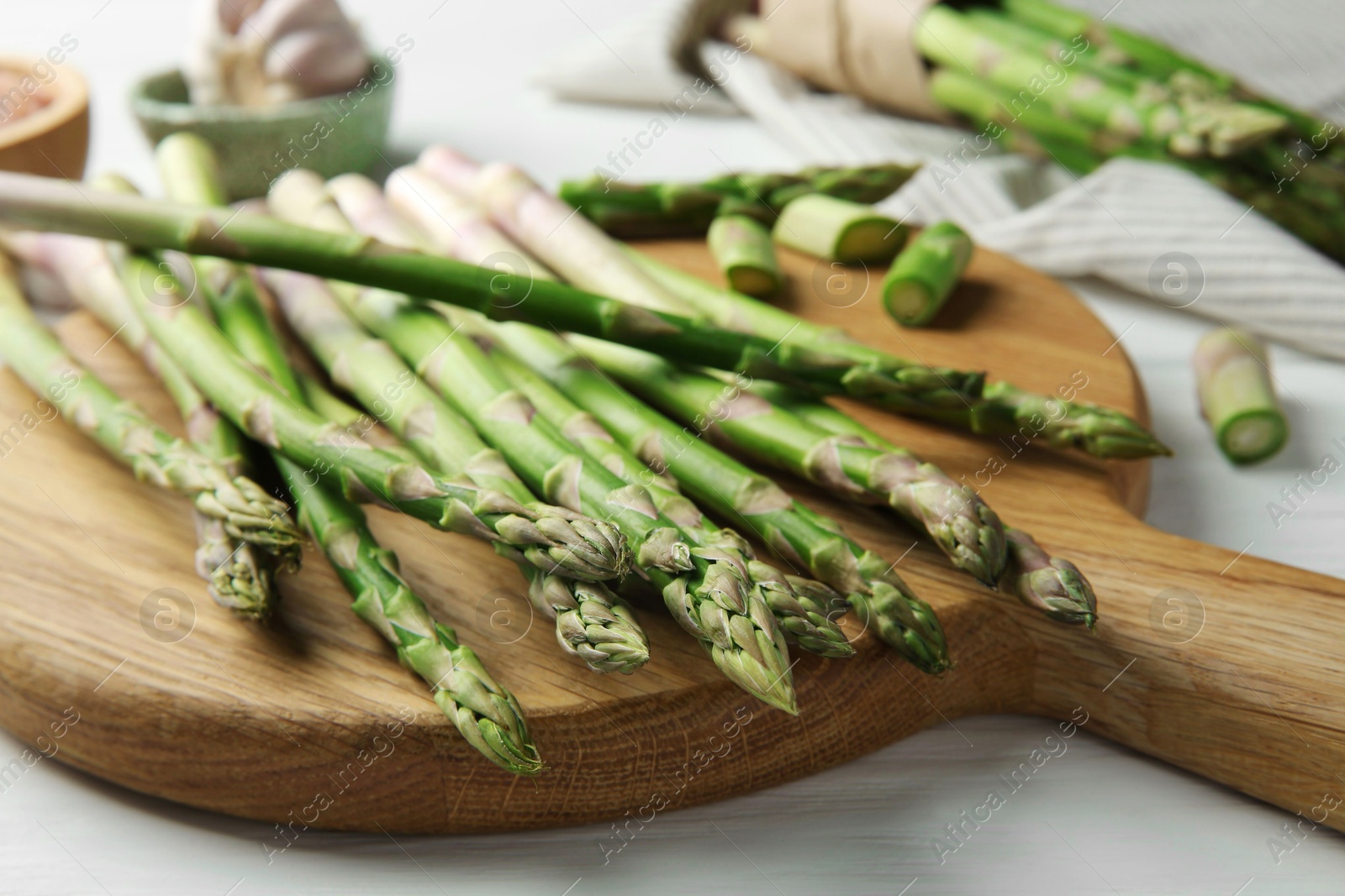 Photo of Fresh green asparagus stems on white wooden table, closeup