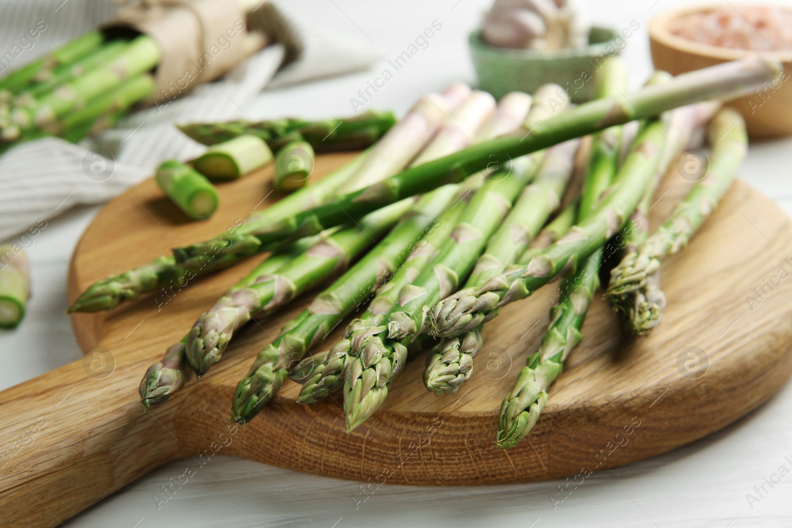 Photo of Fresh green asparagus stems on white wooden table, closeup