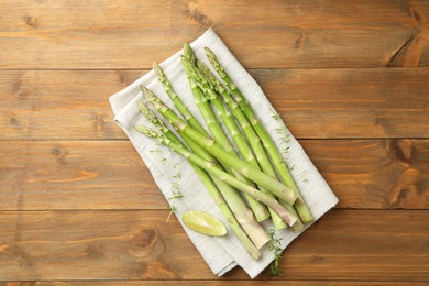 Fresh green asparagus stems and lime on wooden table, top view