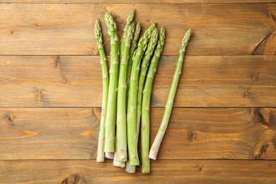 Photo of Fresh green asparagus stems on wooden table, top view