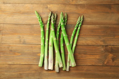 Photo of Fresh green asparagus stems on wooden table, top view